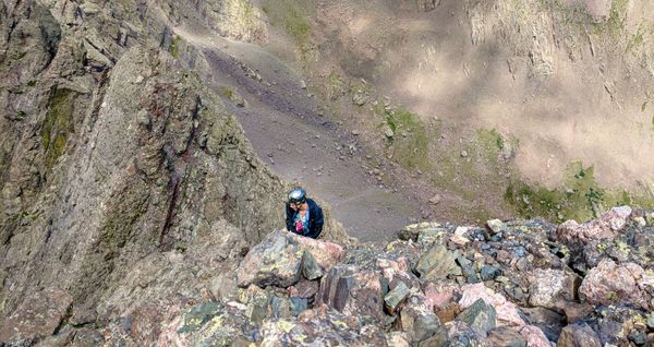 A mountaineer climbing up an steep mountain peak.